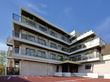 白を基調とした4階建ての建物の各フロアにベランダがあり、敷地内には駐車場がある。