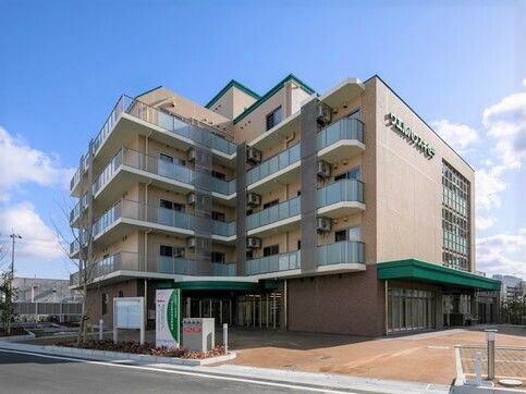 どっしりとしたベージュの7階建ての建物。各フロアにベランダが付き、外壁にはホーム名が書かれている。