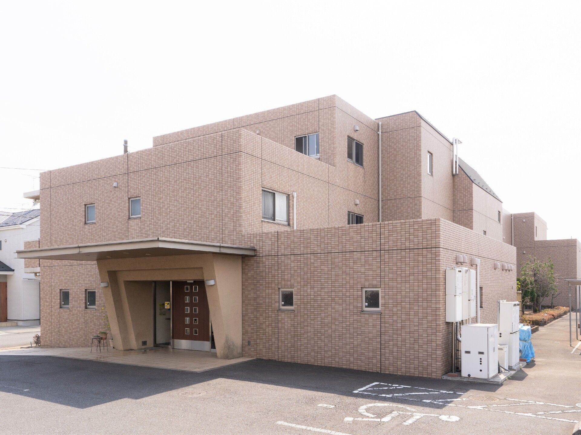 施設外観はピンクがかったレンガ調の外壁。入口には車寄せがついている