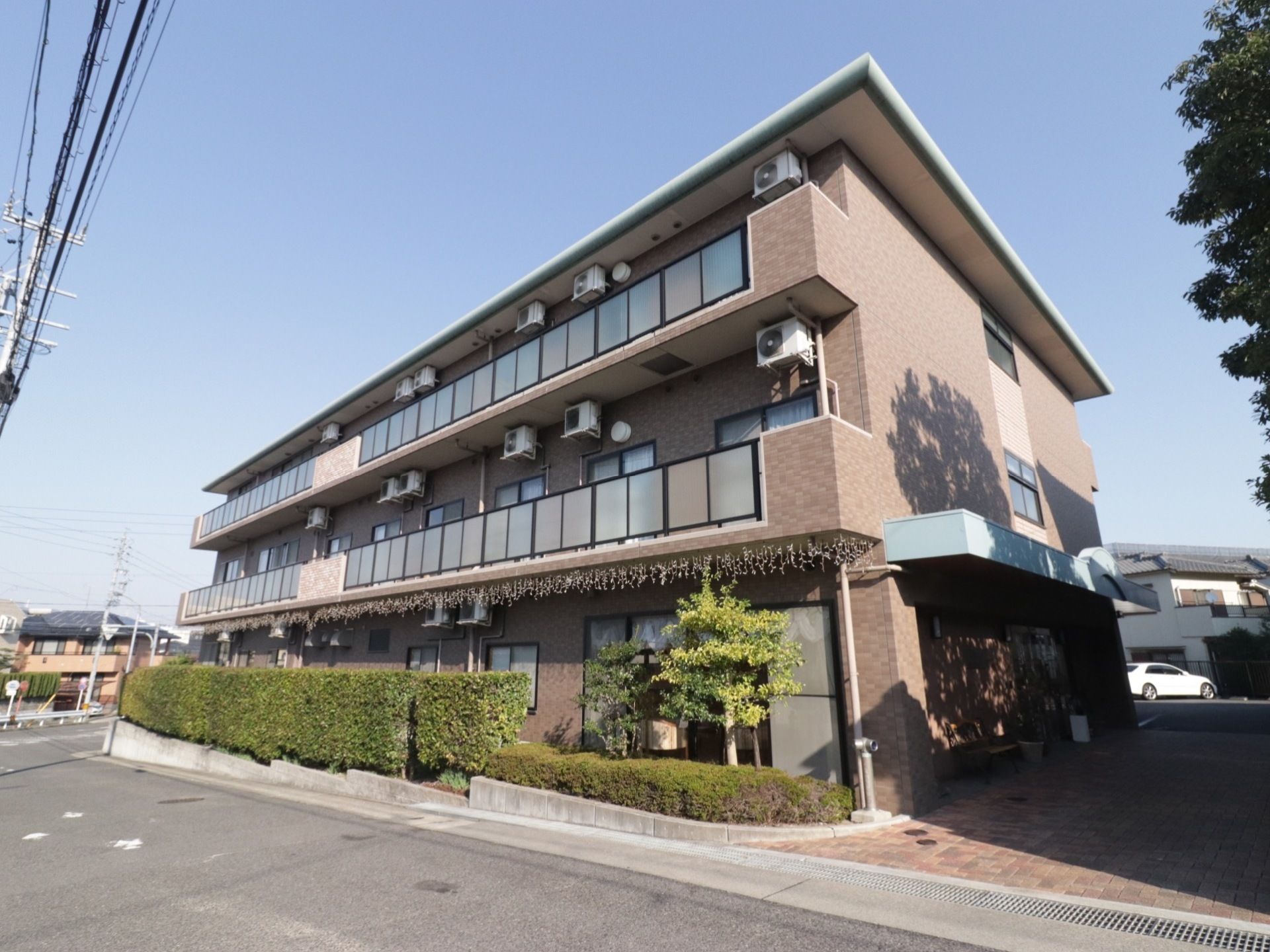 茶色のタイルが組み合わされたようなデザインの外観である。道路沿いには、きれいに手入れされた草木が植えてある。
