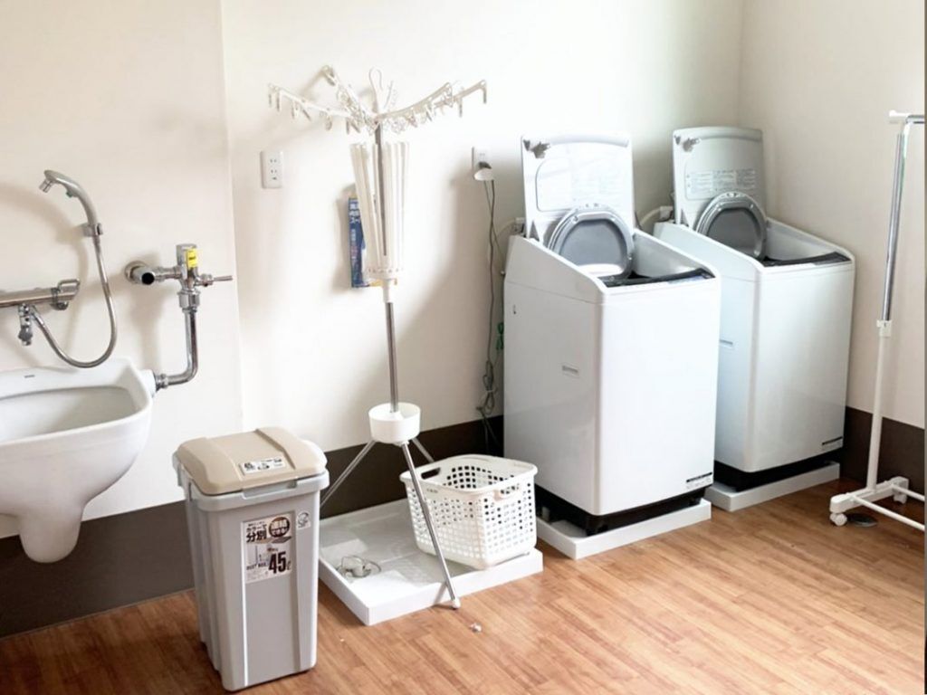 縦型の洗濯機が2つ置かれていて、ゴミ箱や手洗いができる場所もあり、洗濯物干し場も用意されている。