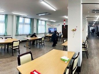 少人数用のダイニングテーブルが複数置かれた食堂には手作りの飾りが飾られている。右側にはまっすぐな廊下がある。