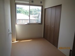 大きな窓が付いたシンプルな部屋。段差のない部屋には木製のドアのクローゼットがある。