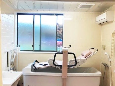ストレッチャータイプのリフトと浴槽タイプの機械が置かれている広い浴室。