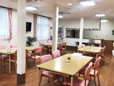 4人掛けのダイニングテーブルが複数置かれている食堂にはテレビがあり、対面式キッチンもある。