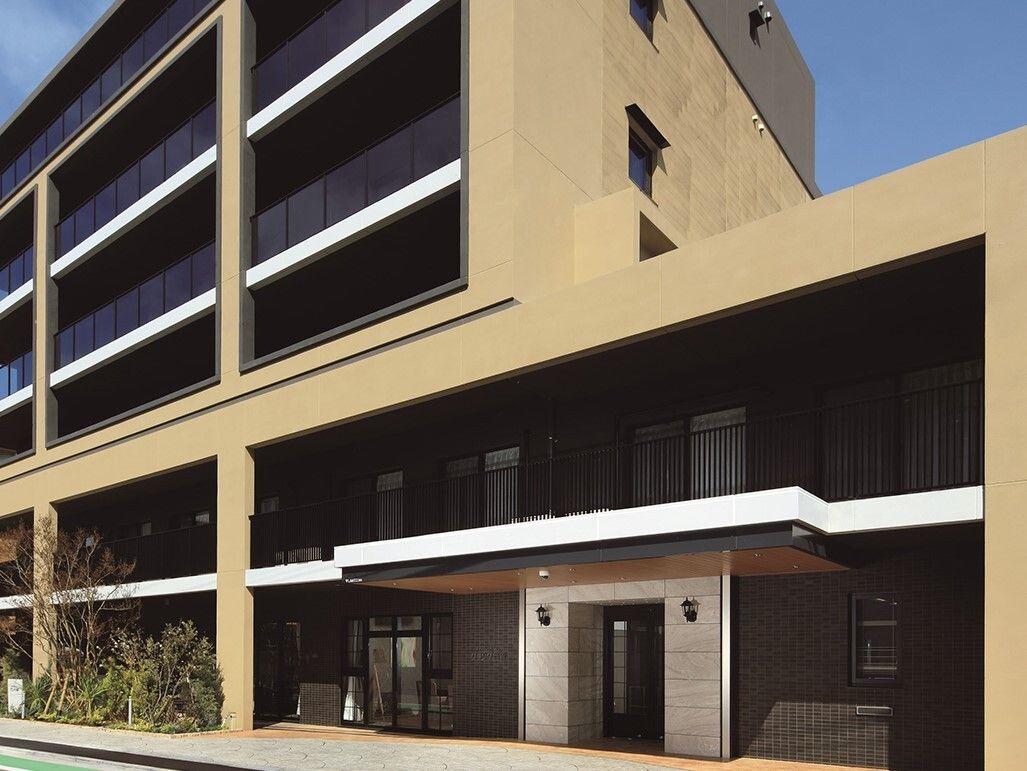 6階建ての建物の1階と2階部分は上のフロアよりも大きく、各フロアにベランダがあり、周辺には植物も植えられている。