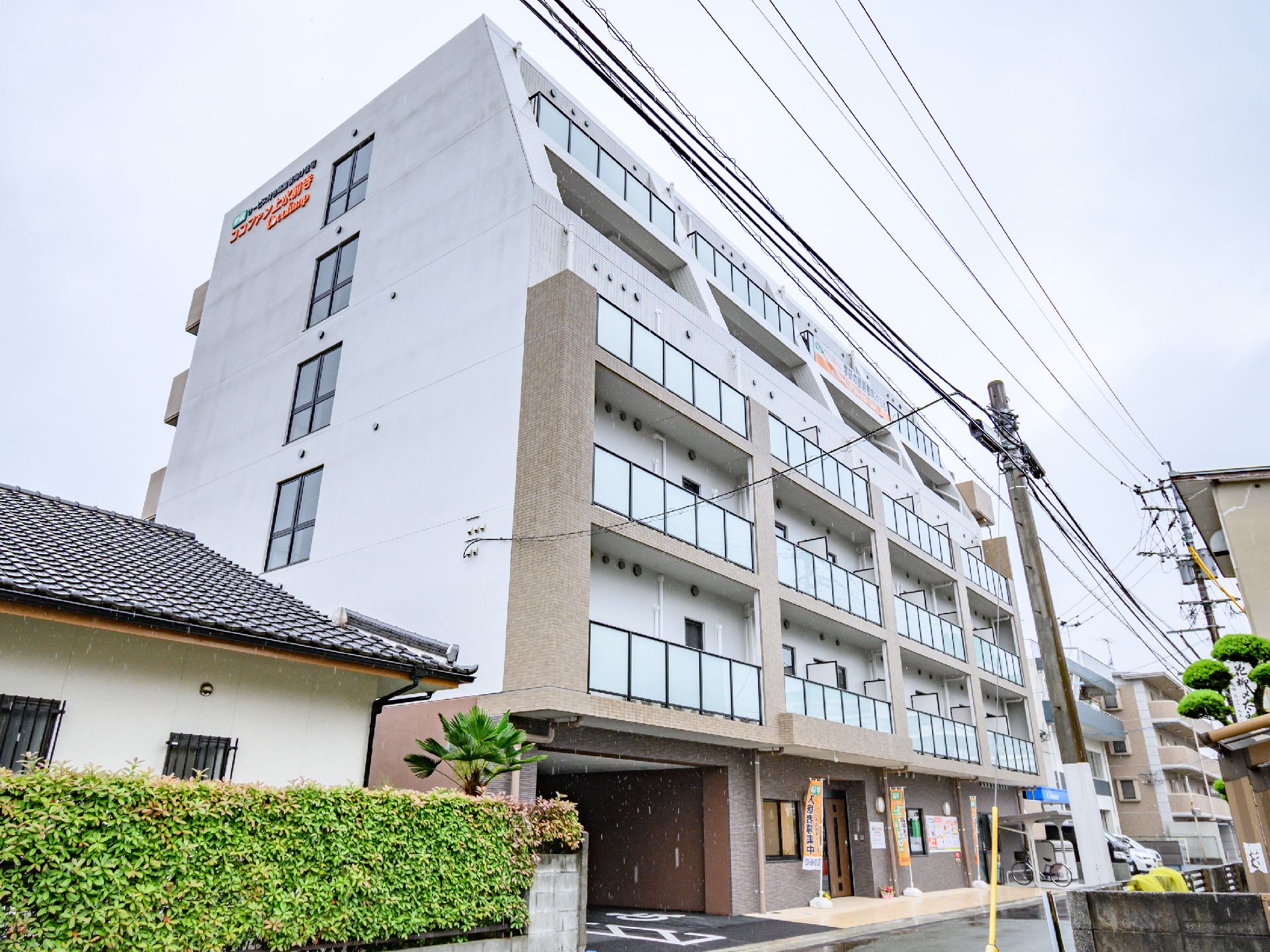 ６階建ての建物の周りには木が植えられ、各フロアにベランダが付いている。ベージュとブラウンの外壁。