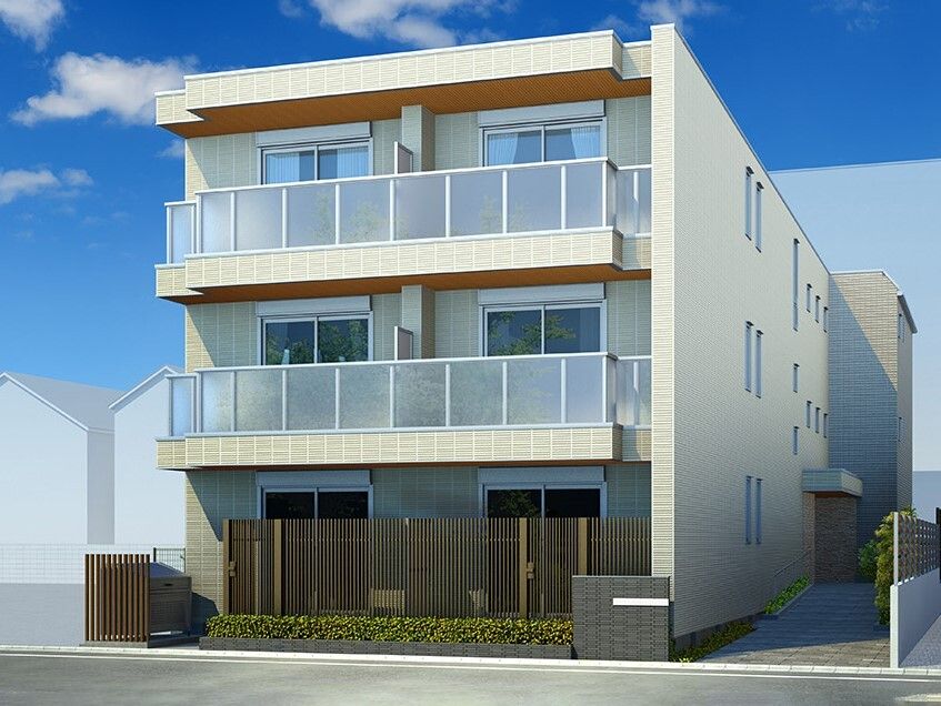 ３階建ての建物は各フロアにベランダがあり、ベージュを基調としている。１階部分にはブラウンのフェンスがあり、低木も植えられている。
