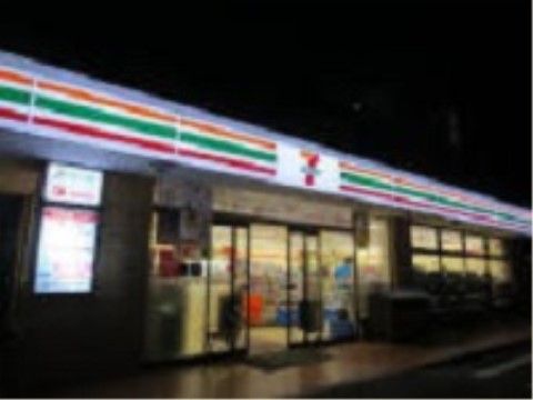 コンビニエンスストアの外観である。1階建てでひさしにオレンジ、緑、赤の横長ラインがあり、その中央にロゴがある。