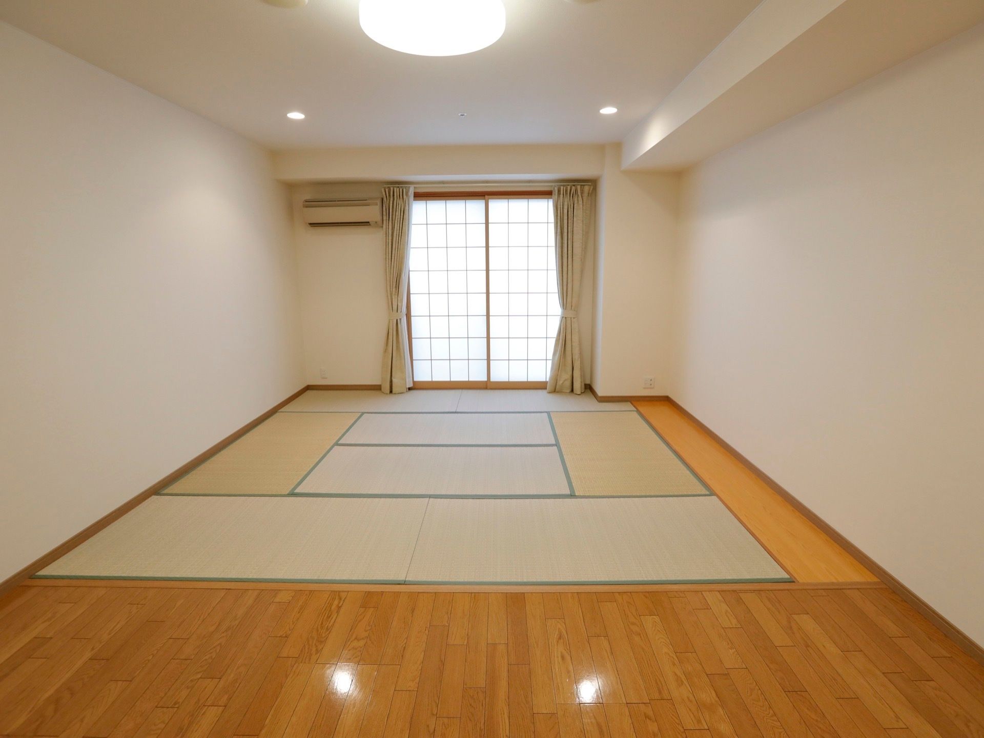 和室と洋室の両方を組み合わせた内装の居室である。奥には障子窓があり、その左横にエアコンが備え付けられている。