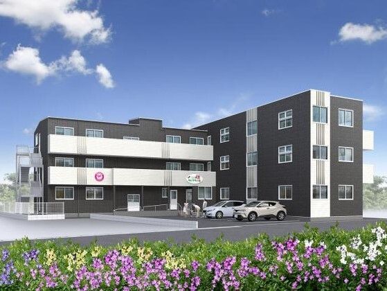 ３階建ての建物は白とダークグレーで敷地内には駐車場があり、建物にはベランダや屋外階段が付いている。