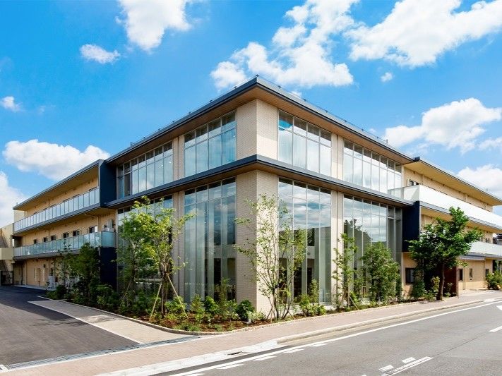 ３階建ての建物は重厚感があり、道路に面している。建物の周りには草木が植えられ、各フロアにベランダもある。