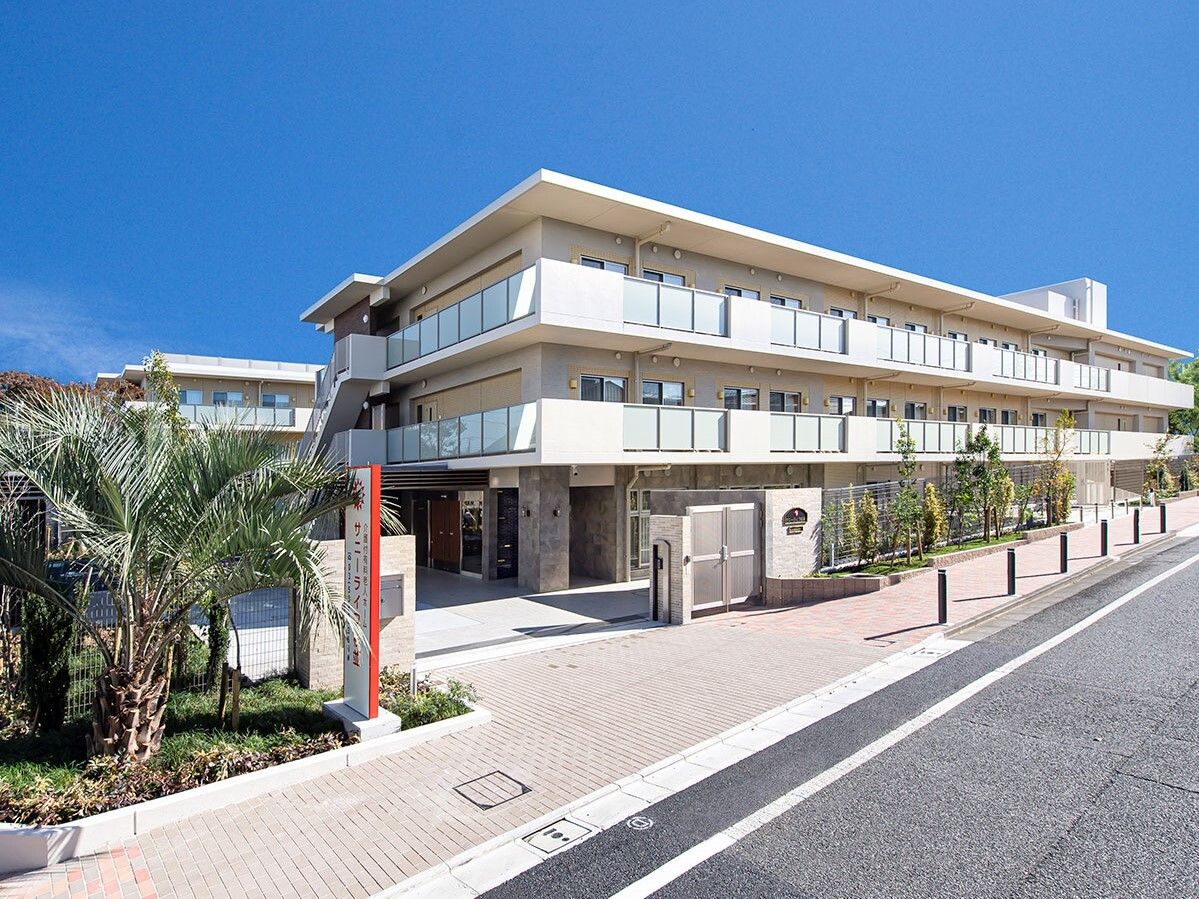 ３階建ての建物は横に長く、周りには草木が植えられている。門の前には館銘板も設置されている。
