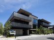 ブラウン系の３階建ての建物はスタイリッシュな外観で、美術館のような造り。建物の周りには草木が植えられている。