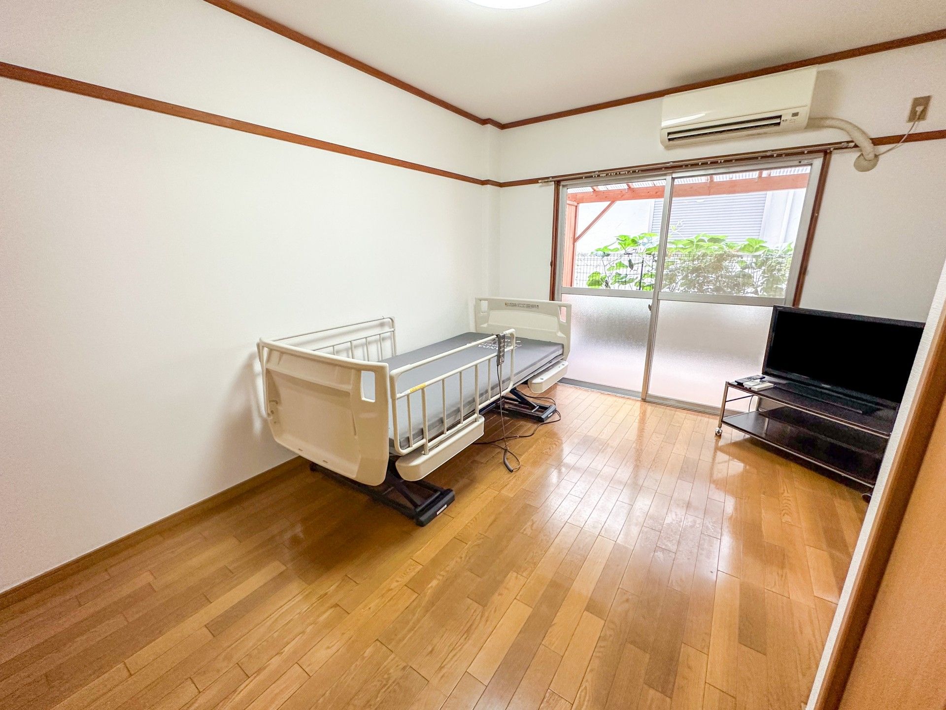 眼鏡をかけた高齢男性が福祉車両から降りようとしているところを手伝っている若いスタッフ。