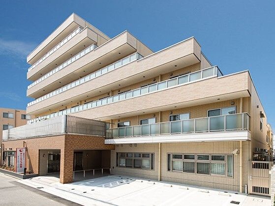 日当たりのいい場所に建っているベージュ系の外壁の建物。玄関のそばには館銘板もある。