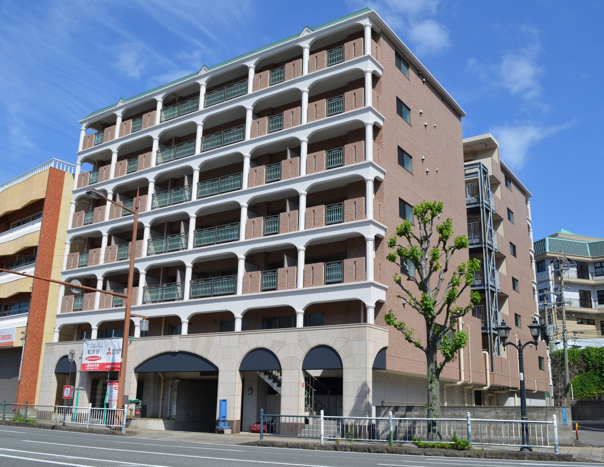 各フロアにベランダがあり、草木が周りに植えられたブラウン系の建物にはたくさんの窓も付いている。