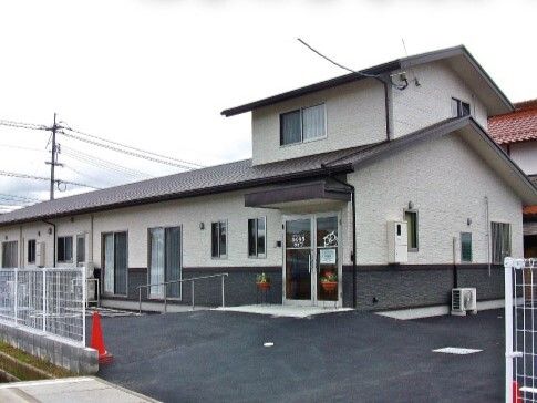 2階建ての建物はグレーの屋根があり、玄関に屋根が付いている。2階部分の面積はかなり小さい。