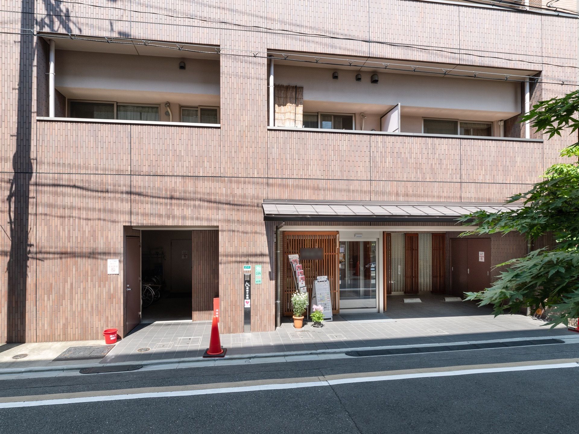 伽羅色を基調としたブロック調の壁があたたかみのある、上品な佇まいの建物である。入口付近には、駐車場がある。