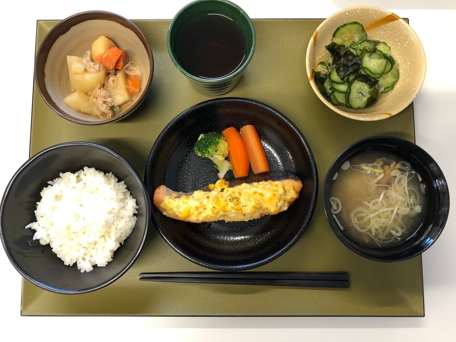 お盆にセットされた3品のおかずとご飯、お味噌汁お盆に、お茶
