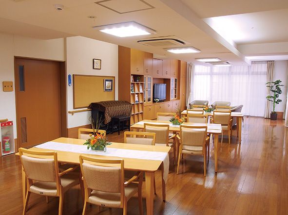 窓がある広い部屋にダイニングセットが間を空けて並んでいる。センサー付きの手洗いが２箇所ある。台の周囲には手すりがある。