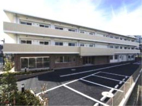 横方向に大きい3階建ての施設がある。施設のそばには駐車場があり、車をご利用の方でも安心である。玄関のそばまで車で向かうことができる。