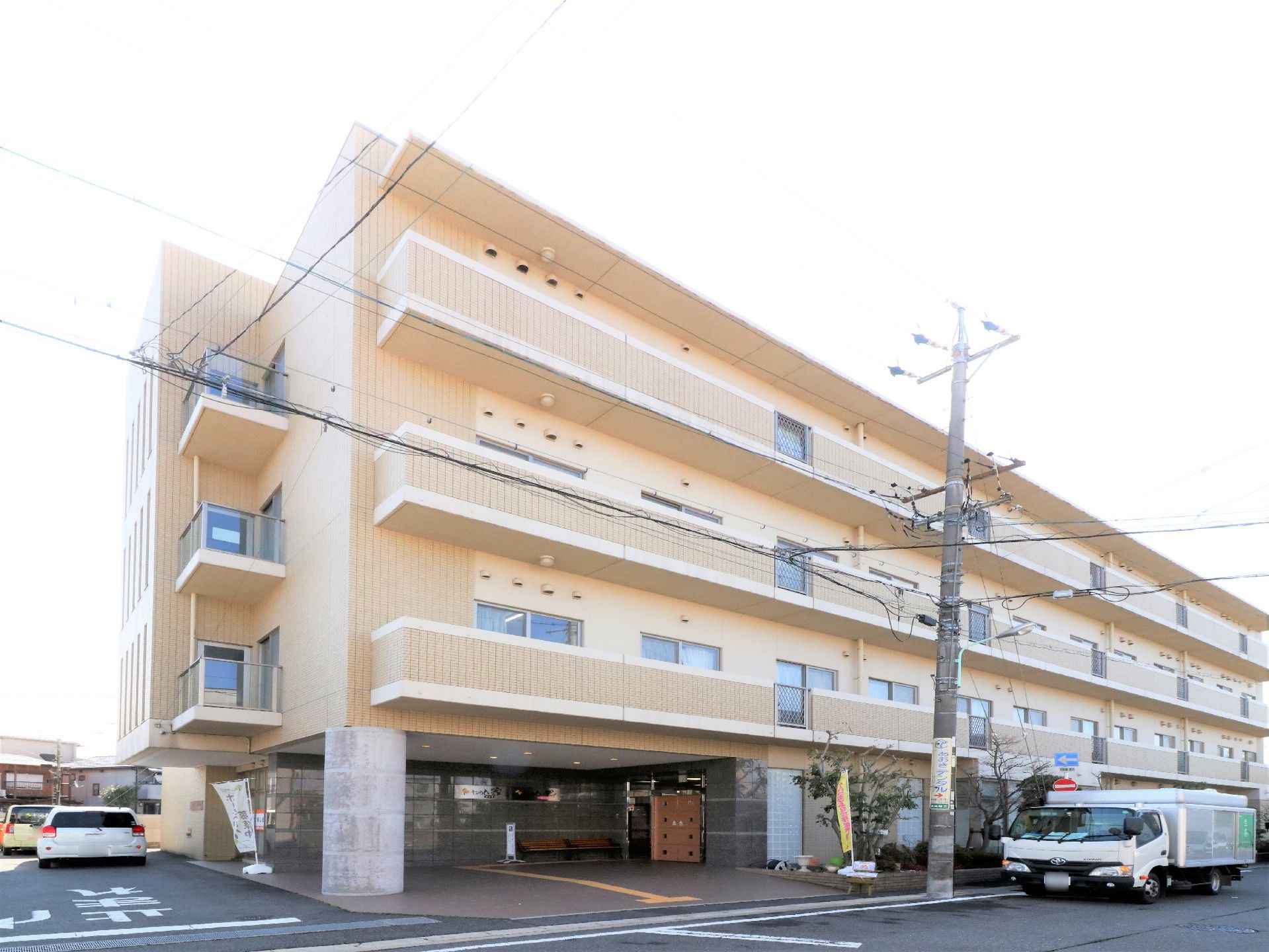 黄色系のタイルで壁面が構成されており4階建ての建物である。道路から入り口まで段差がない。駐車場が併設されている。
