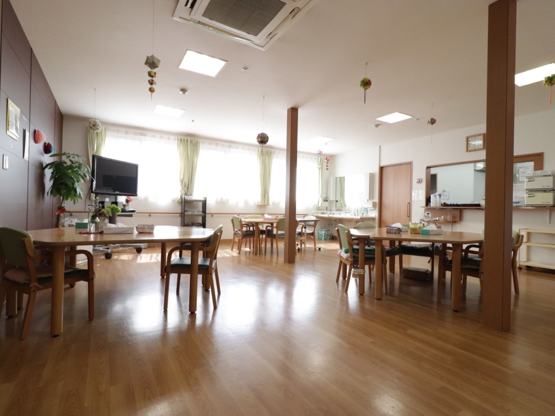 五角形のテーブルで各テーブルの上にティッシュが置いてある。天井には丸い飾りが吊り下げてある。日光が良く入る。
